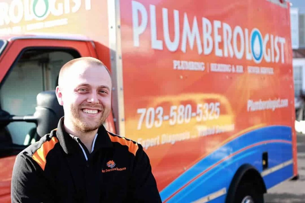 Technician smiling while standing in front of a service truck outside.
